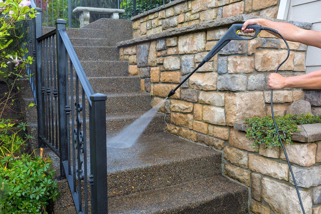 Washing the house front entrance stair steps and stone walls with pressure power washer